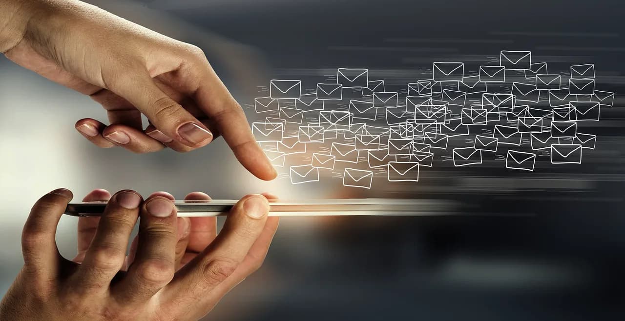 Koyu zeminde akıllı telefonu tutan ellerden çıkıp akan dijital zarf simgeleri
