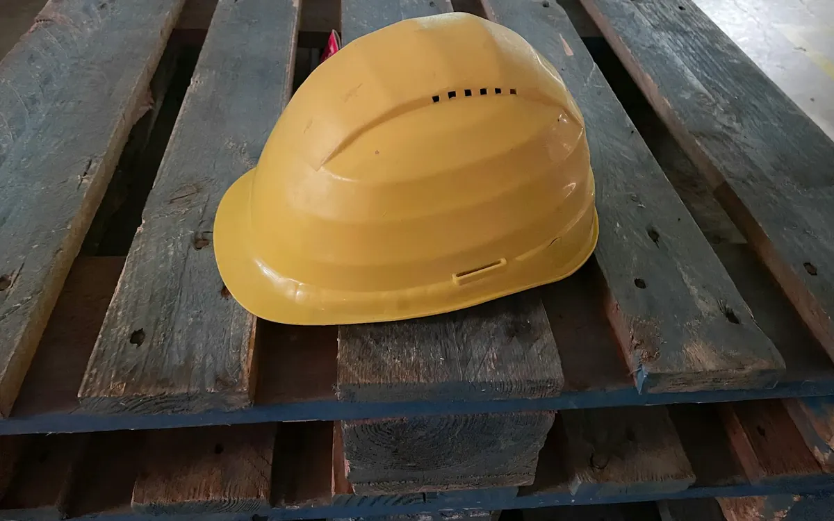 Ahşap bir paletin üzerinde duran sarı baret